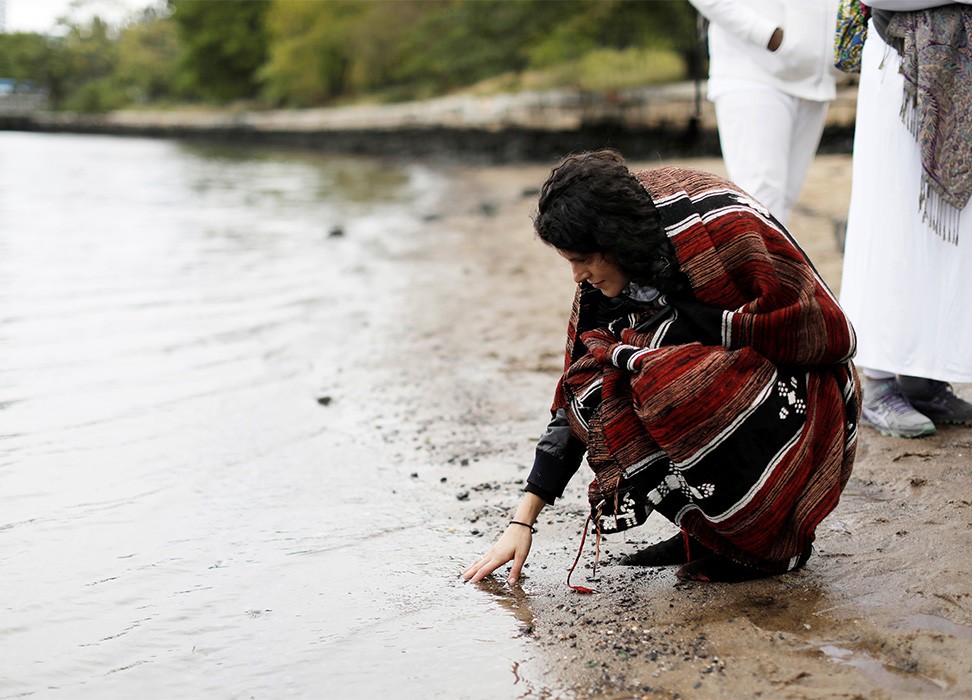 土著妇女触碰水面。©供图：路透社