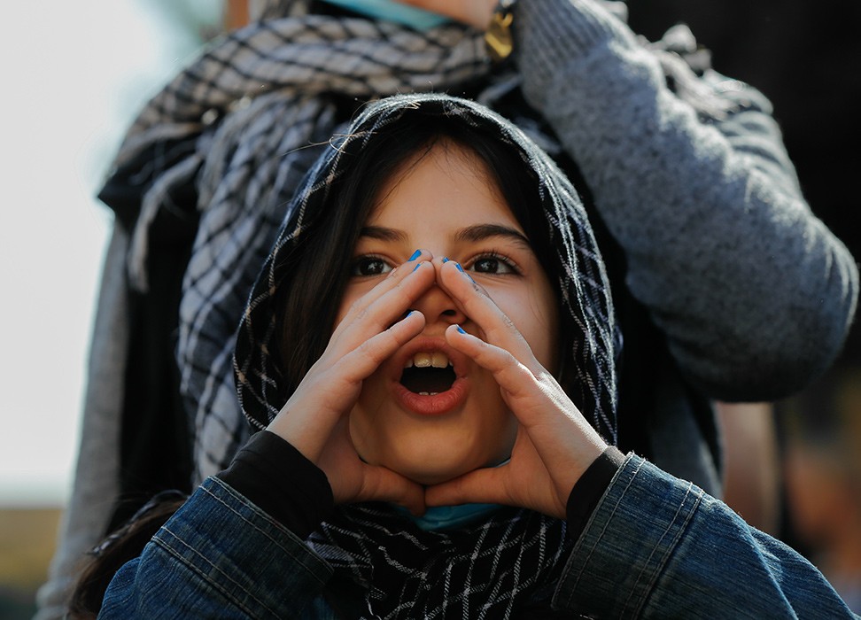 Cover photo of un Human Rights Annual Appeal 2023. A young girl wearing a headscarf cups her hands around her mouth as she shouts during a protest in Beirut, Lebanon, 10 February 2021 © Florient Zwein/Reuters 