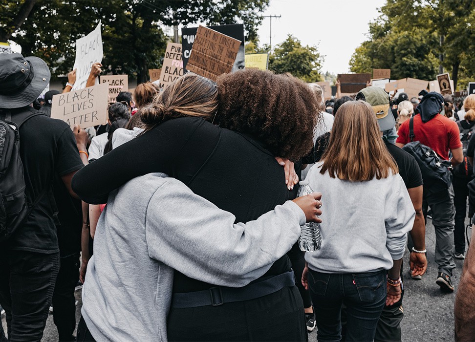 2020年6月10日，美国西雅图，反对种族正义示威人群中两名妇女相互拥抱。© Duncan Shaffer/UNSPLASH