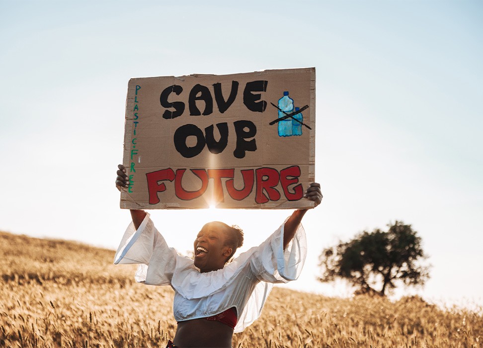一位妇女站在野外，手持标语呼吁提高对气候变化的认识。图片来源：盖蒂图片社/Leo Patrizi
