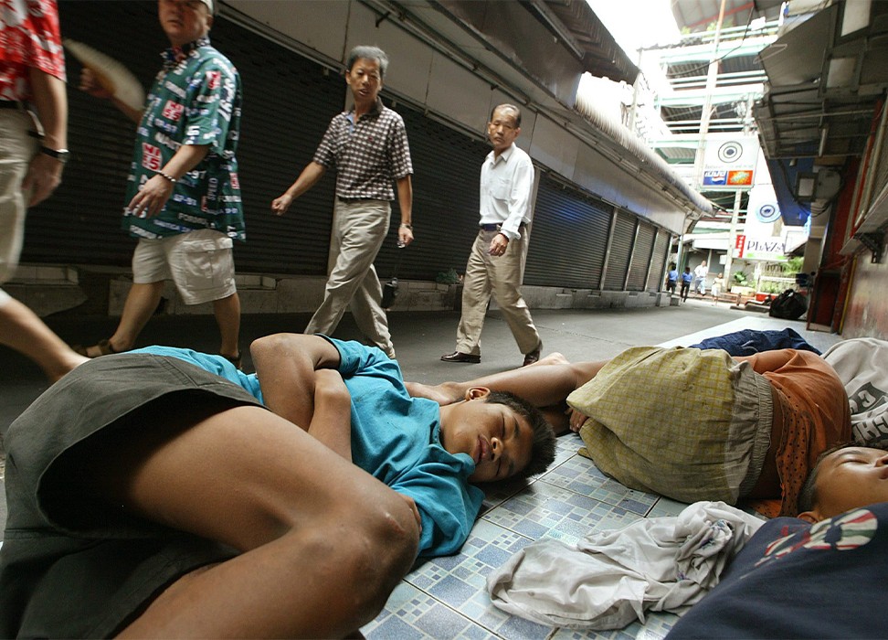Des enfants sans abri dorment sur un trottoir de Bangkok. © EPA/ Vinai Dithajohnn