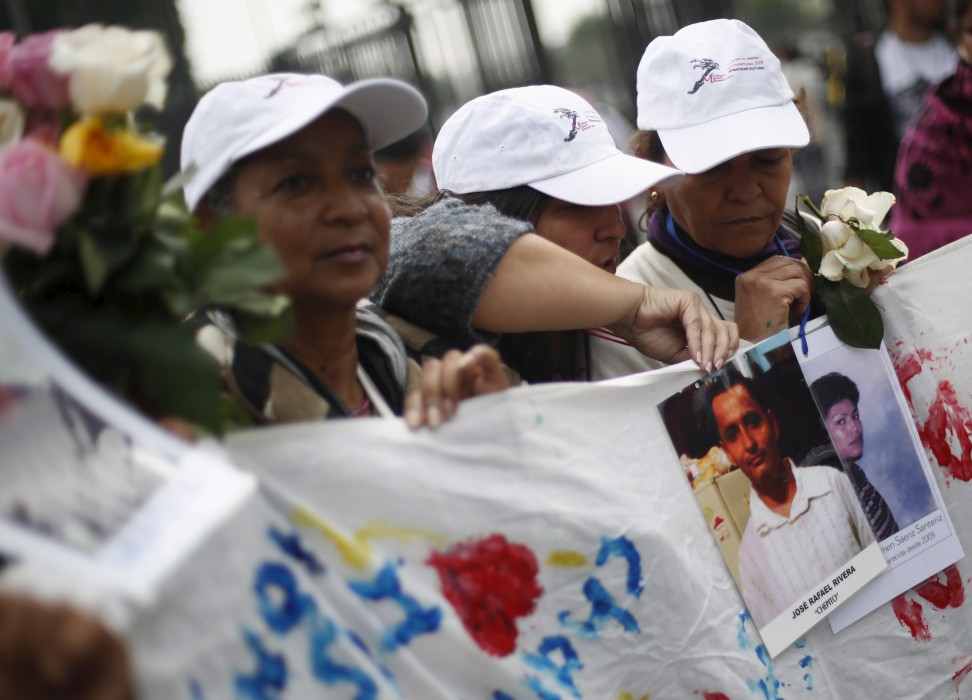 “中美洲母亲车队”（Caravana de Madres Centroamericanas）的妇女们举着失踪移民的照片。图片来源：路透社／Edgard Garrido