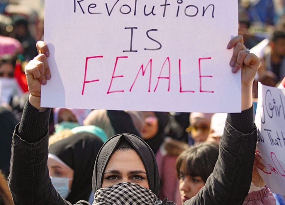 Woman holding up a protest sign that reads 'Revolution is Female'