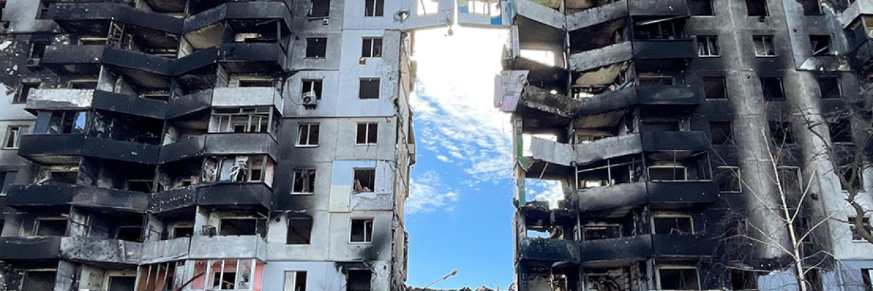 2022年4月7日，在乌克兰基辅州布恰地区的博罗江卡小镇，一名老年人拄着拐杖经过遭俄罗斯军队空袭后的公寓大楼废墟，乌克兰军队已重新占领了该地区。