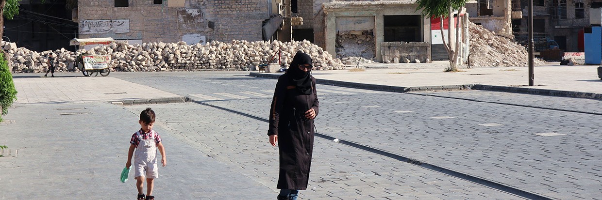 امرأة وطفلها يمران أمام الأنقاض في حلب بسوريا، في 17 حزيران/ يونيو 2022 © رويترز