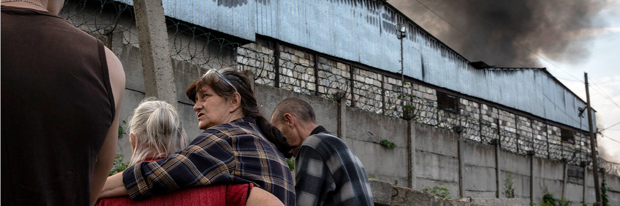 A woman hugs her mother while they observe the chain of black smoke from a car depot caused by Russian artillery strikes in Lysychansk, Luhansk, 28 May 2022.