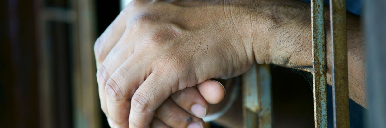 Hand shot of a prisoner behind bars. © Getty Images