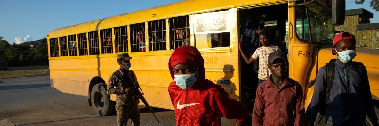 Un miembro del Ejército dominicano vigila un autobús de la Dirección Nacional de Migración, que se utiliza para transportar a 52 migrantes haitianos que serán deportados por el paso fronterizo de Comendador, en Comendador, República Dominicana, el 22 de noviembre de 2021.  Crédito: EPA-EFE/Orlando Barria