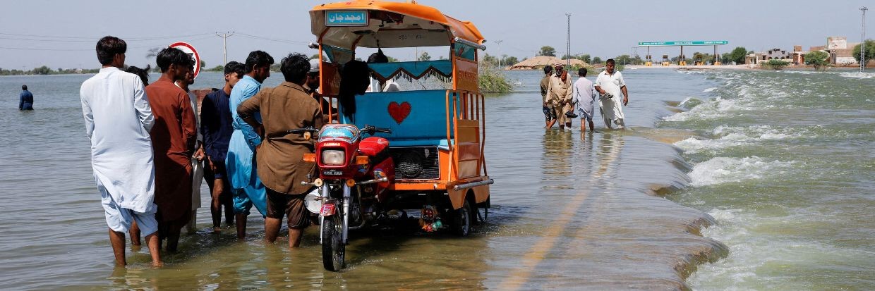 Plusieurs personnes déplacées se tiennent sur une route inondée, suite aux pluies et aux inondations durant la mousson à Sehwan, au Pakistan, le 16 septembre 2022. Reuters
