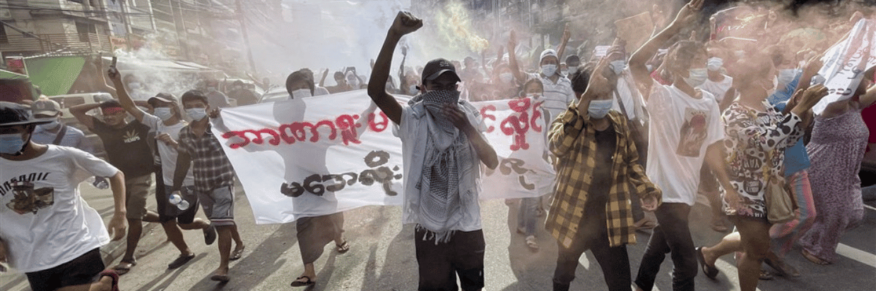 Manifestantes sostienen carteles y bengalas mientras marchan en una protesta contra el golpe militar en la zona céntrica de Yangón, Myanmar, 3 de julio de 2021. © EPA-EFE