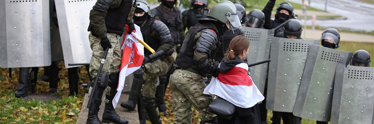 A woman wearing a historical white-red-white flag of Belarus is taken away by a law enforcement officer during a rally to reject the presidential election results in Minsk, Belarus November 8, 2020. © REUTERS/Stringer