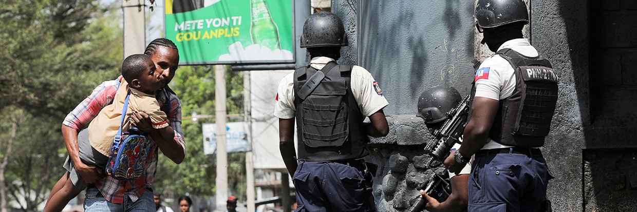 2023年3月3日，海地首都太子港，一名男子在帮派暴力事件中抱着儿子离开学校寻找掩护。©路透社/Ralph Tedy Erol