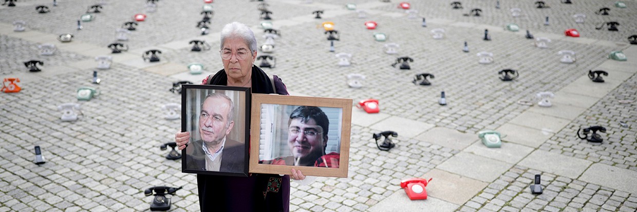 Fadwa Mahmoud holds images of her husband and son, who have been missing since 2012, outside a court in Koblenz, Germany, following the trial of a Syrian intelligence officer in January 2022.  © Thomas Frey/Pool via REUTERS