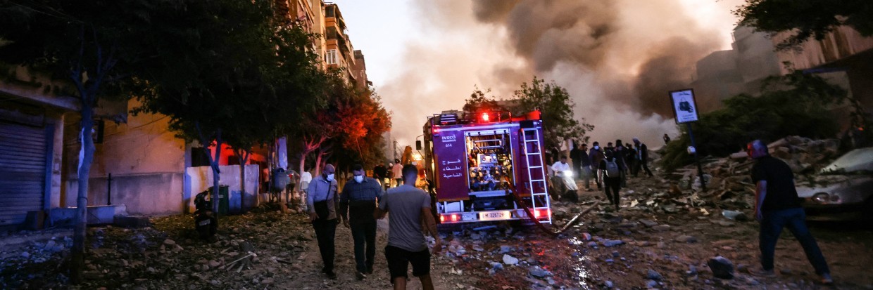 People and a fire truck rush to the scene of an Israeli air strike in the Haret Hreik neighborhood of Beirut's southern suburbs on September 27, 2024.