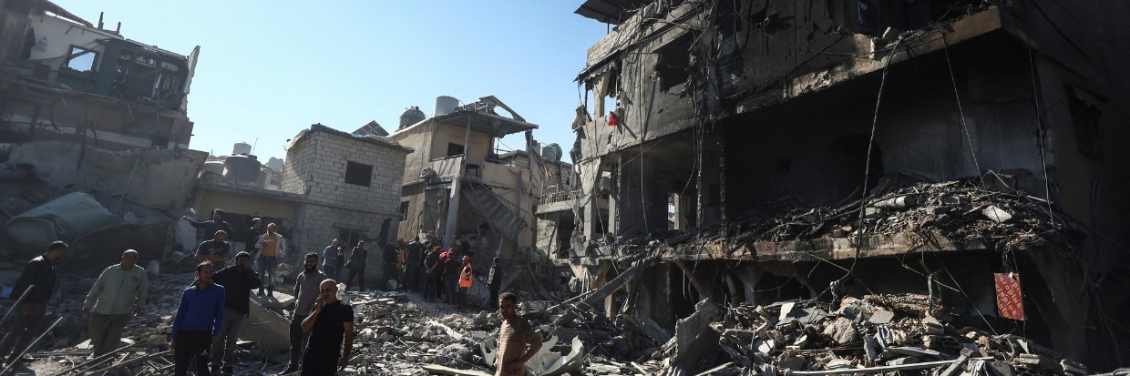 People stand on the rubble of a demolished building after an Israeli strike near the Rafik Hariri University Hospital, amid ongoing hostilities between Hezbollah and Israeli forces, in Beirut, Lebanon October 22, 2024. 