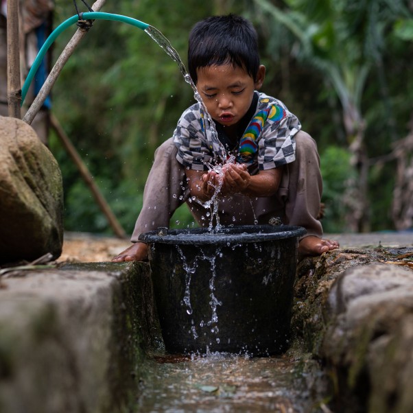 A boy washes his face in front of his home. © UNICEF/UN0353548/Ijazah