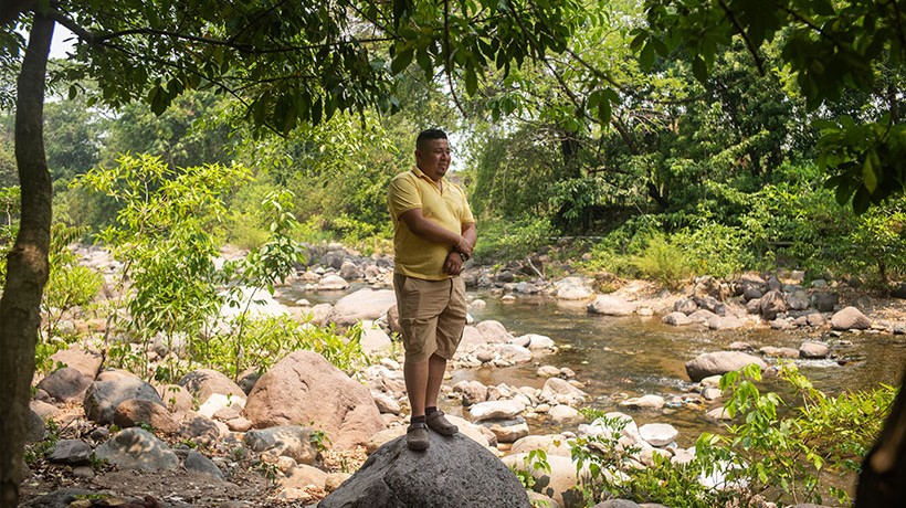 A man standing in a rock near a river