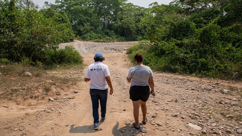 Two women walk in a dirty road that used to be a river