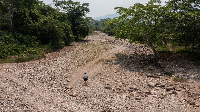 A woman walking through a rocky area that used to be a river