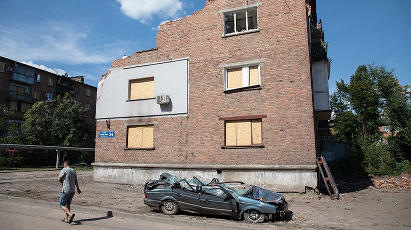 A man walks past apartments and a car destroyed by a missile attack in Kharkiv. The extensive use of explosive weapons in populated areas have killed and injured tens of thousands of people in the course of the conflict. © Vincent Tremeau/OHCHR