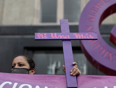 A woman holds a cross reading "no more missing" during a march demanding justice for the victims of gender violence and femicides in Mexico City, Mexico. © REUTERS/Raquel Cunha. 