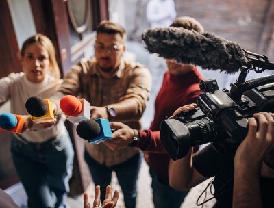 Group of people, female politician confronted by journalists with microphones, credit: Getty 