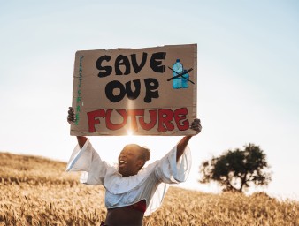 Woman standing in nature with a message to raise awareness against climate change © Getty/Leo Patrizi.