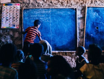 A schoolboy writes on a chalkboard in Ethiopia. © Betsy Arce