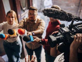 Group of people, female politician confronted by journalists with microphones, credit: Getty 