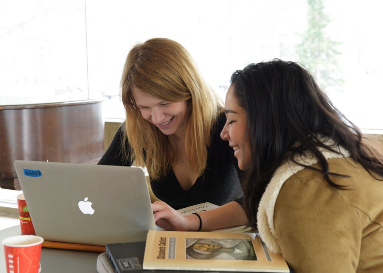 Two women looking at a laptop, smiling. ©Wikimedia