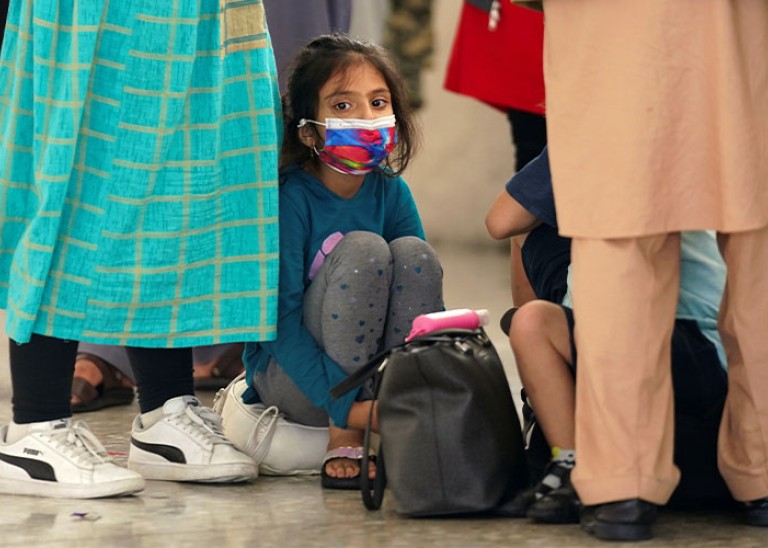 An Afghan girl waits with other refugees for a bus to take them to a processing center upon arrival at Dulles International Airport in Dulles, Virginia, U.S., August 26, 2021. REUTERS/Kevin Lamarque