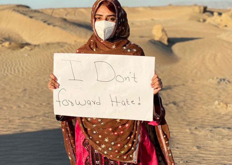 A girl carrying a sign "I Don’t Forward Hate"