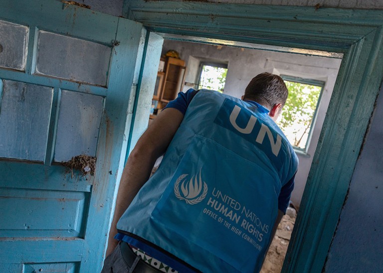 A UN Human Rights officer surveys a destroyed home in a village that was occupied by Russian troops before it was recaptured by Ukraine. © Vincent Tremeau/OHCHR